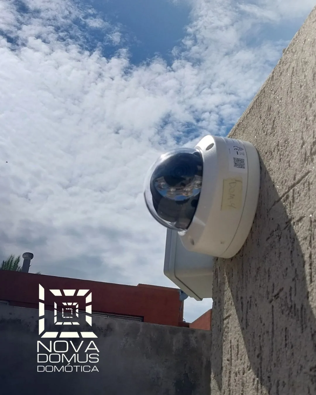 Cámara de seguridad domo instalada en una pared exterior, con el cielo despejado de fondo