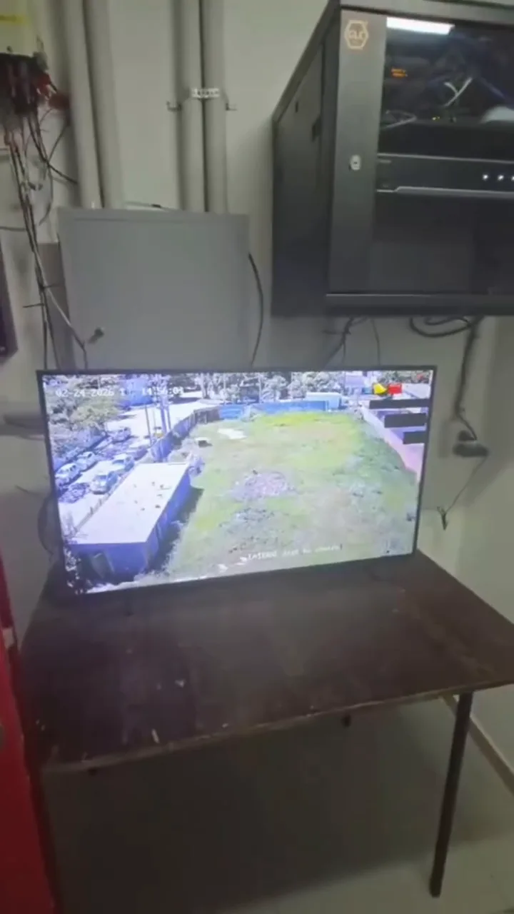 Rack de networking con NVR y monitor mostrando la vista aérea de cámaras de seguridad de un edificio