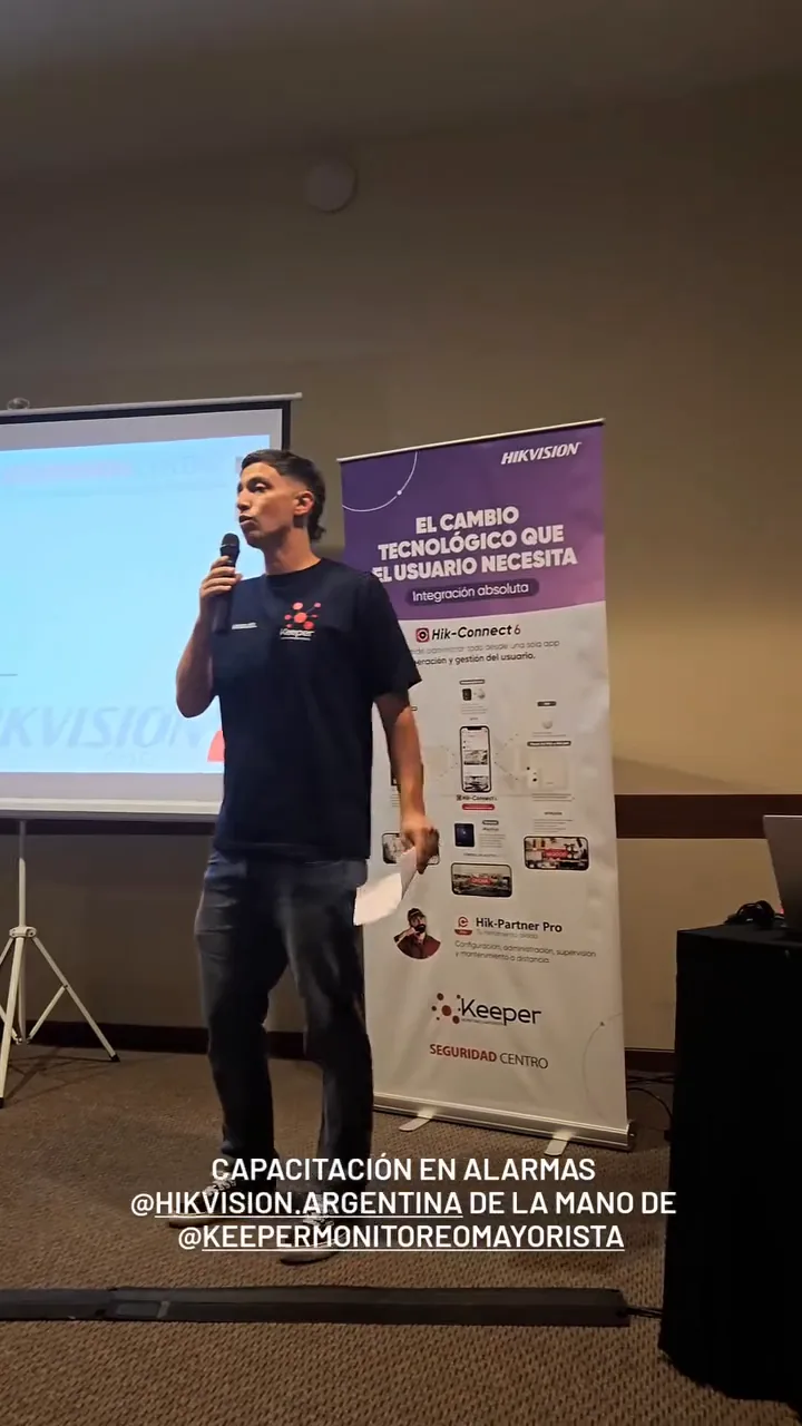 Orador presentando una capacitación en alarmas Hikvision, con un banner de la marca de fondo