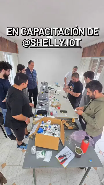Grupo de personas alrededor de una mesa con dispositivos Shelly durante una capacitación técnica