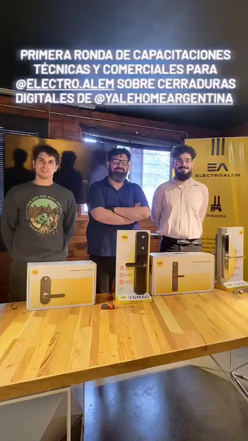 Tres integrantes de Nova Domus y Electro Alem posando con cajas de cerraduras digitales Yale sobre una mesa