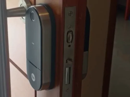 Cerradura inteligente Yale montada en la puerta, con el frente alineado contra la chapa testera del marco