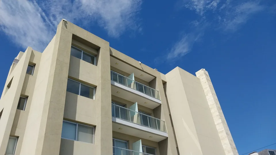 Cámara domo de videovigilancia instalada en el borde de un edificio, con la fachada completa de fondo